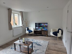 Ett vardagsrum med en tv, två fåtöljer, ett soffbord och en mönstrad matta.