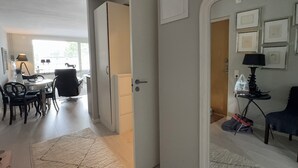 Una habitación con comedor, una puerta que da a otra estancia y una mesita de noche con lámpara.
