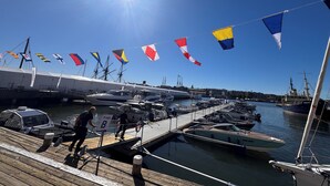 Un puerto deportivo con barcos amarrados, un muelle de madera y un cielo despejado.