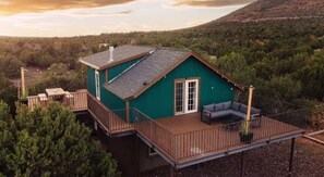 A single-story house with a deck, surrounded by dense forest, and a clear sky. - Wrap-around deck, cozy home, gateway to the Canyon. (Williams)