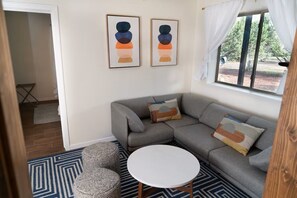 A room with a grey sofa, a round white table, and two abstract paintings on the wall. - Wrap-around deck, cozy home, gateway to the Canyon. (Williams)