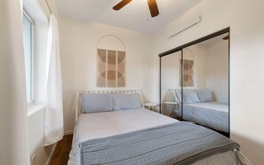 A bedroom with a bed, a window, a ceiling fan, and a mirror. - Wrap-around deck, cozy home, gateway to the Canyon. (Williams)
