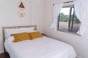 A bedroom with a bed, white curtains, and a window with a view. - Wrap-around deck, cozy home, gateway to the Canyon. (Williams)