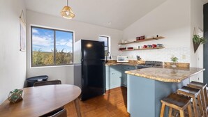 A modern kitchen with a black refrigerator, a dining table, and bar stools. - Wrap-around deck, cozy home, gateway to the Canyon. (Williams)