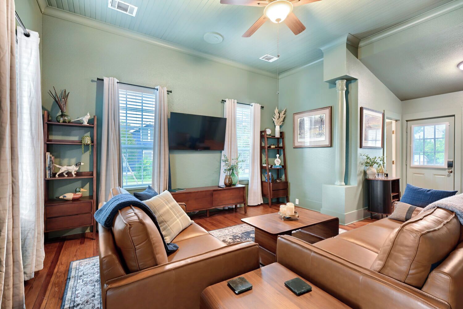 A living room with a brown leather sofa, a wooden coffee table, and a television.