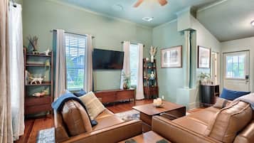 A living room with a brown leather sofa, a wooden coffee table, and a television.