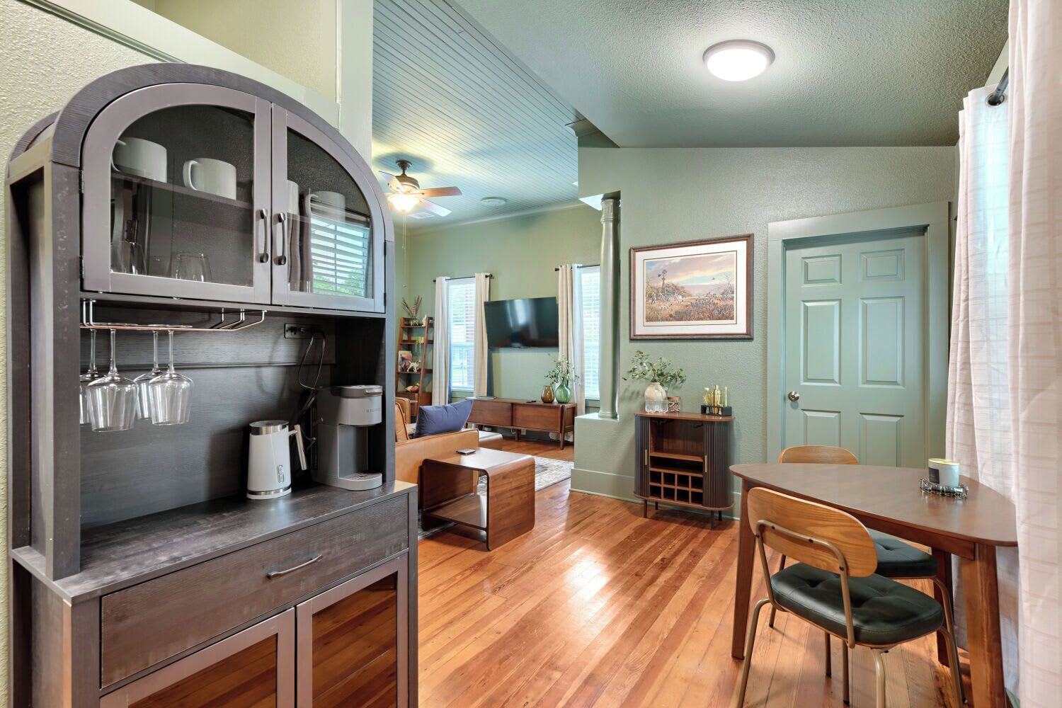 A living room with a sofa, coffee table, and a TV. There is a dining area with a table and chairs.
