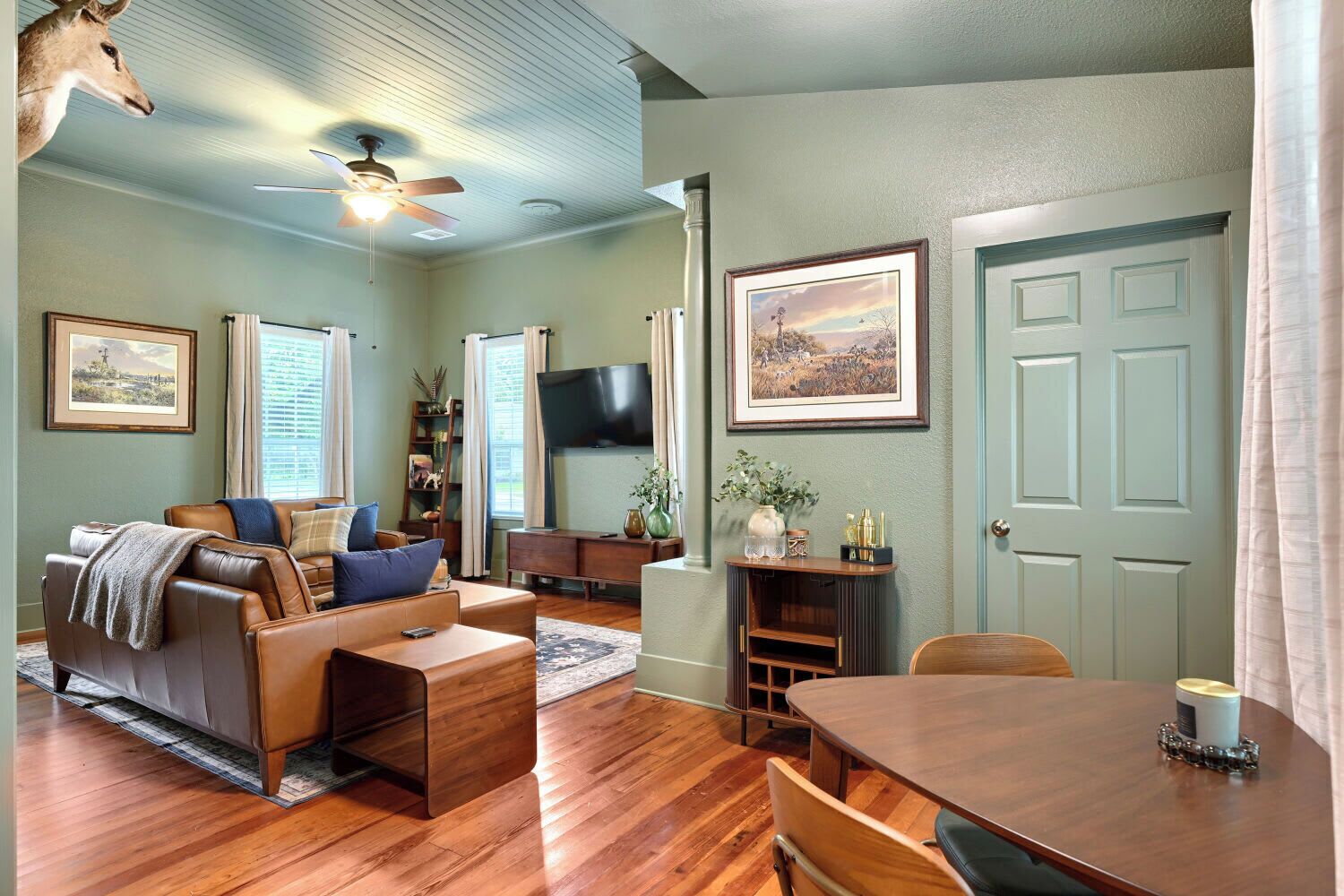 A living room with a sofa, coffee table, TV, and a dining table with chairs.