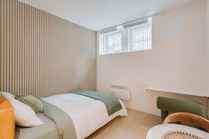 A bedroom with a bed, a chair, a radiator, and a window. - 003 Cook - Loft in the Heart of Old Quebec (Québec)