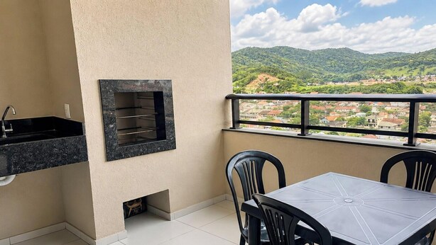 Ein Balkon mit Tisch und Stühlen, einem Waschbecken und einem Fenster mit Blick auf eine hügelige Landschaft.