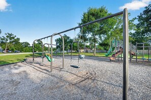 Ein Spielplatz mit Schaukeln, einer Rutsche und einer Kletterkonstruktion.