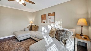 A modern living room with a sectional sofa, a ceiling fan, and artwork on the wall. - Family Getaway: 4BR, BBQ Yard, Steps to Park (La Porte)