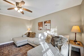 A modern living room with a sectional sofa, a ceiling fan, and artwork on the wall. - Family Getaway: 4BR, BBQ Yard, Steps to Park (La Porte)