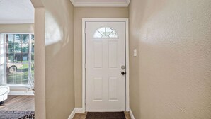 A hallway with a white door, beige walls, and a window with blinds. - Family Getaway: 4BR, BBQ Yard, Steps to Park (La Porte)