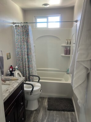 Ein Badezimmer mit Toilette, Badewanne, Duschvorhang und einem Fenster.