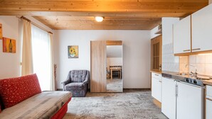 A room with a sofa, a chair, a dining table, and a kitchen area. - Appartements Sonnberg - Top 1 (Bad Hofgastein)
