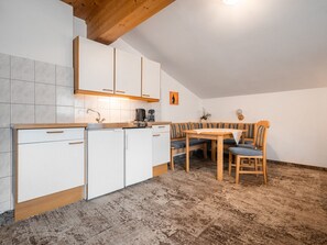 Eine kleine Küche mit weißen Schränken, einer Holzausziehtafel und einem Essbereich mit einer Bank und Tisch.