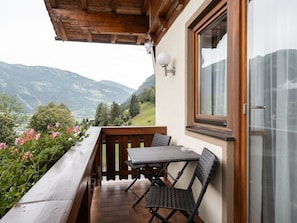 A balcony with a wooden railing, a table with chairs, and a view of mountains. - Appartements Sonnberg - Top 2 (Bad Hofgastein)