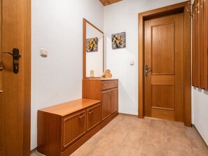 Ein Korridor mit einer Holztür, einem Holzschrank und einem Spiegel.