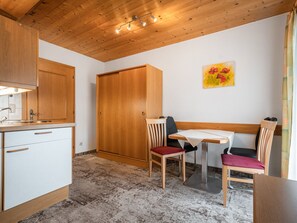 Eine kleine Küche mit Holzschränken, einem Spülbecken und einem Essbereich mit Tisch und Stühlen.