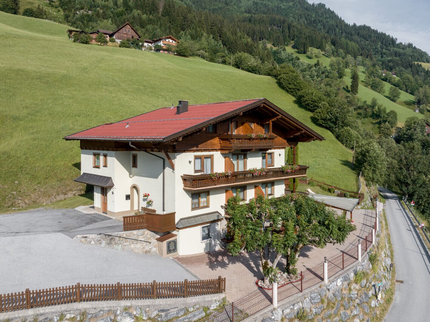 Eine zweistöckige Chalet mit rotem Dach, Holzbalkonen und einem Steinfundament.
