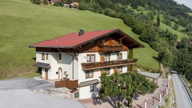 Un chalet de dos pisos con techo rojo, balcones de madera y base de piedra.