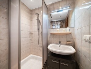 Ein modernes Badezimmer mit Bodendusche, Badewanne, Waschtisch und Spiegel.