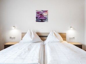 Ein Doppelbett mit weißer Bettwäsche, zwei Nachttische und Wandleuchten.