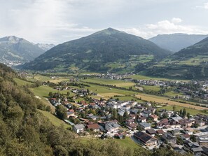 A town nestled in a valley with a mountain backdrop, featuring a mix of residential buildings and open fields. - Appartements Sonnberg - Top 4 (Bad Hofgastein)