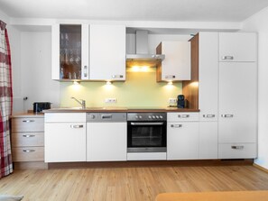 A compact kitchen with white cabinets, a built-in oven, a coffee maker, and a toaster. - Appartements Sonnberg - Top 5 (Bad Hofgastein)