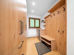 A compact kitchen with wooden cabinets, a window with blinds, a radiator, and a small shelf with a plant. - Appartements Sonnberg - Top 5 (Bad Hofgastein)
