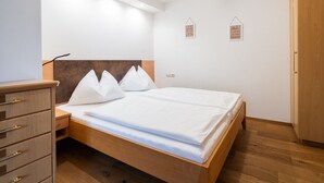 Un dormitorio con cama de madera, mesita de noche, cómoda y armario.
