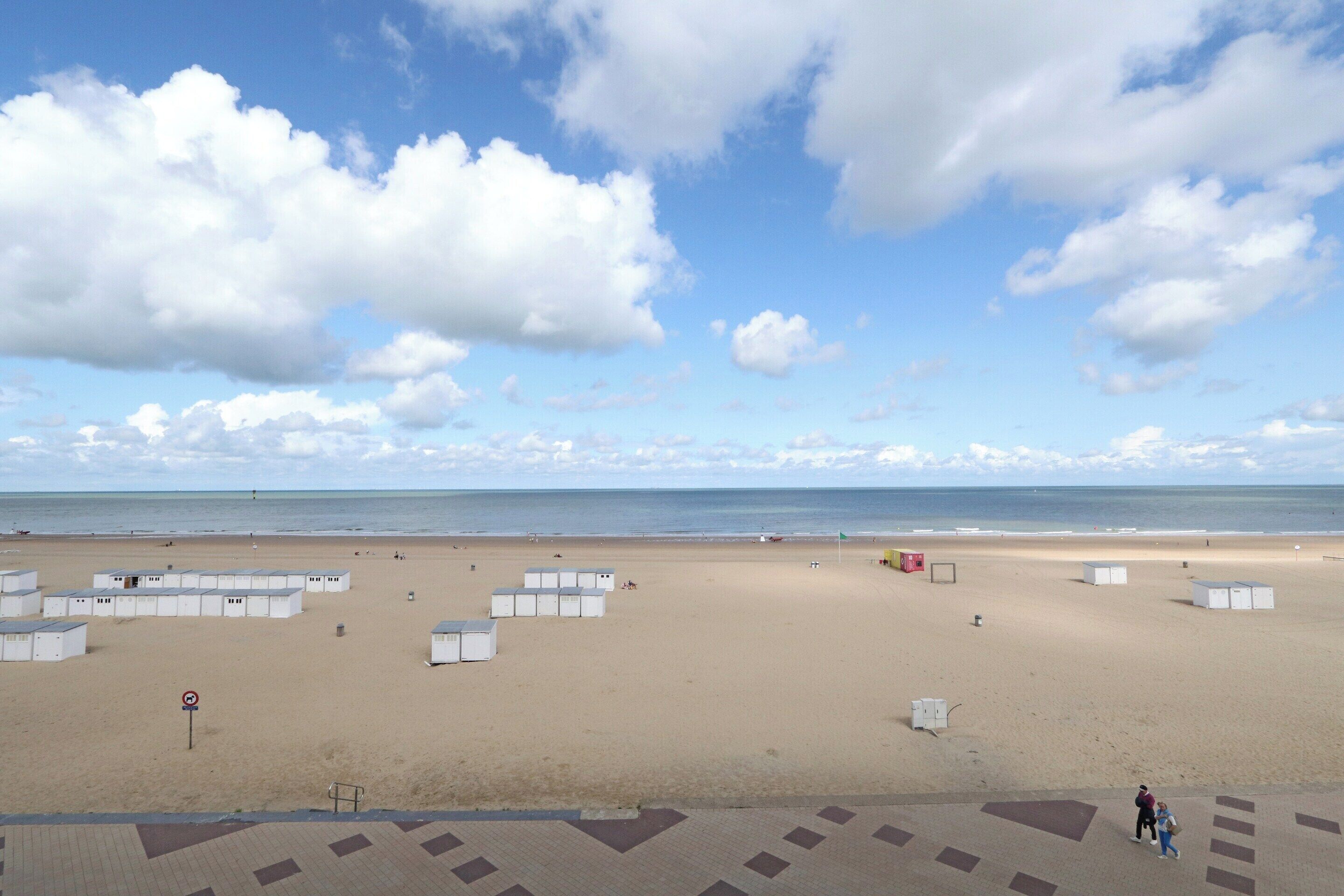 Una playa con cabañas blancas y cielo despejado.