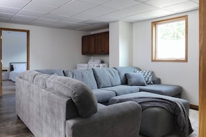 Una sala de estar con un sofá modular gris, un mueble de madera y una ventana con vistas.