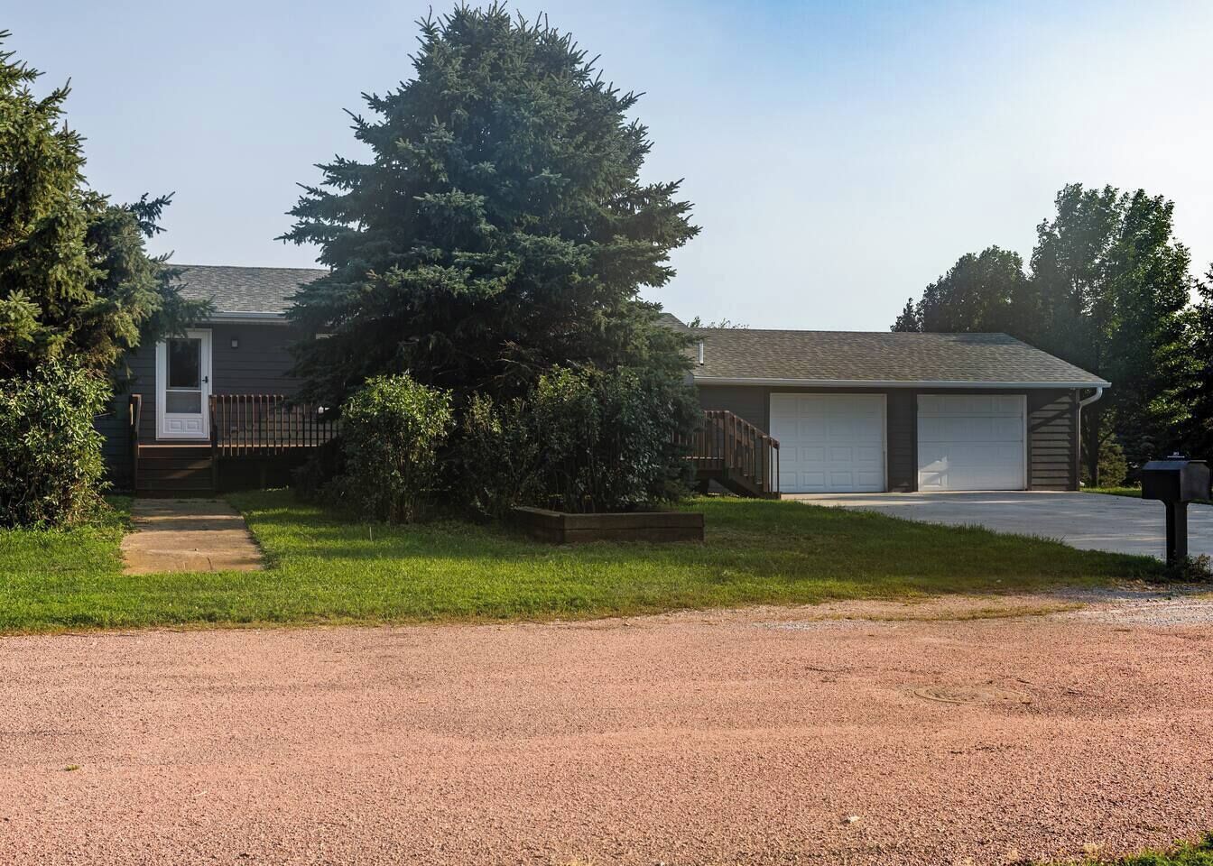 A two-story residential building with a front porch, a garage, and a driveway.