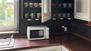 A kitchen with a microwave, open cabinets with dishes, and a window. - A spacious house with a garden by the sea, close to the beach and the pier. (Mosty)