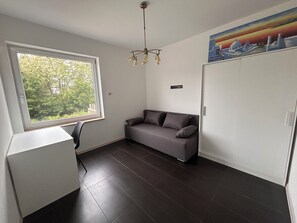 A room with a window, a sofa, a desk, and a painting on the wall. - A spacious house with a garden by the sea, close to the beach and the pier. (Mosty)