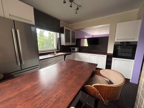 A modern kitchen with a wooden island, stainless steel appliances, and white cabinetry. - A spacious house with a garden by the sea, close to the beach and the pier. (Mosty)