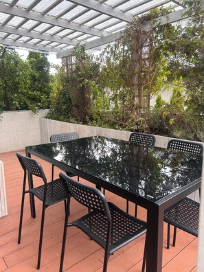 An outdoor patio with a glass-top table and black metal chairs. - A spacious house with a garden by the sea, close to the beach and the pier. (Mosty)