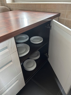 A kitchen with a wooden countertop and a cabinet with multiple white plates. - A spacious house with a garden by the sea, close to the beach and the pier. (Mosty)