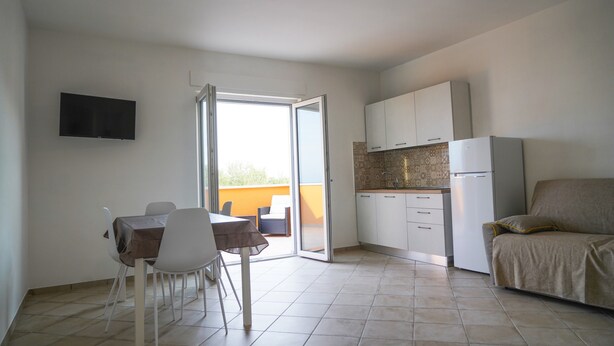 A compact living space with a dining area, kitchenette, and a sofa.