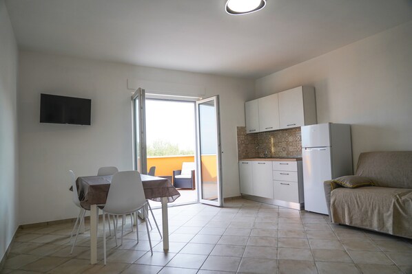 A compact living space with a dining area, kitchenette, and a sofa.