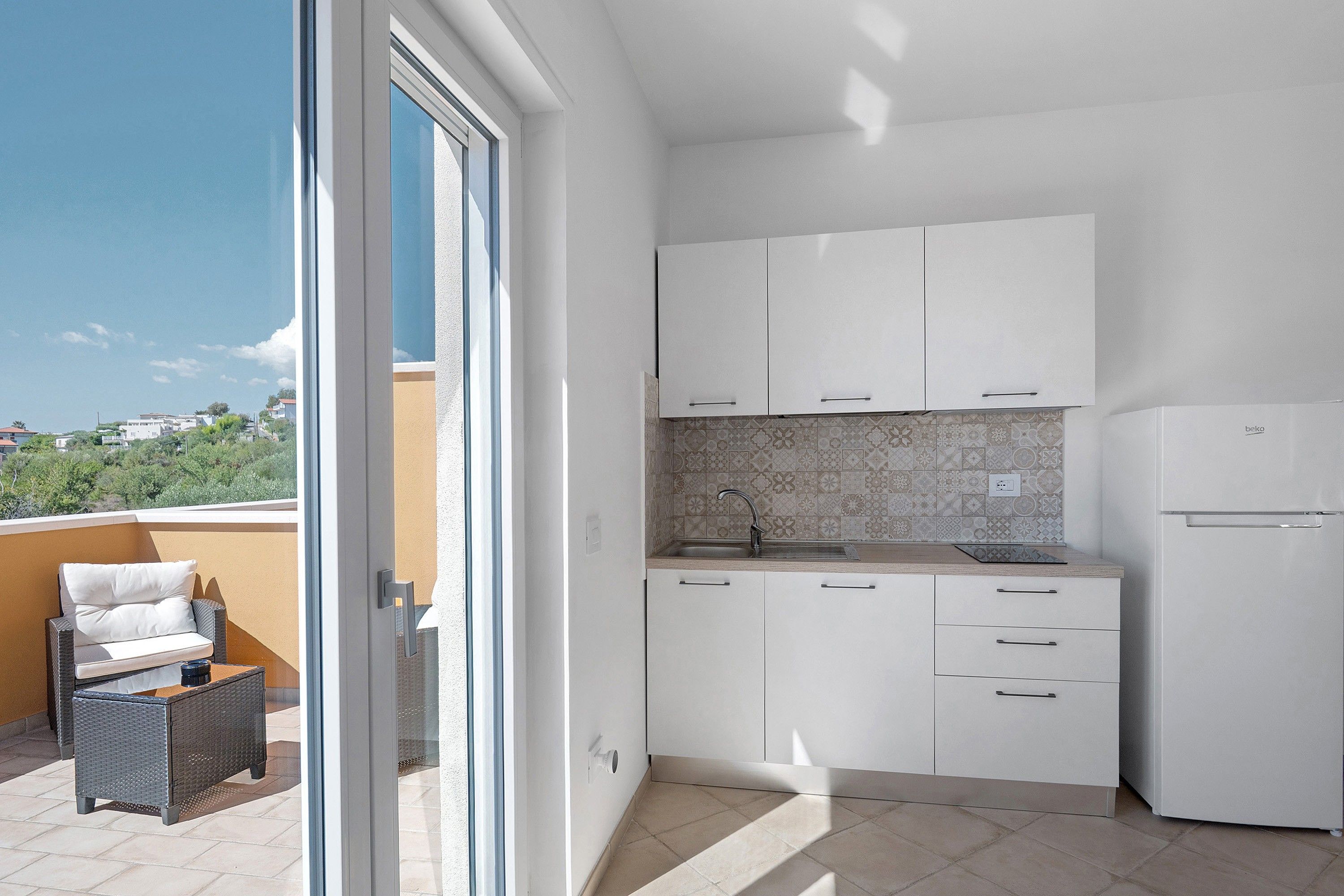 A modern kitchen with white cabinets, a built-in oven, and a sink.