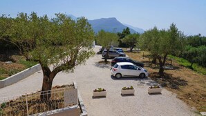 A parking area with cars and trees, a clear sky, and a mountain in the background.
