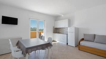 A compact living space with a dining area, kitchenette, and a sofa.