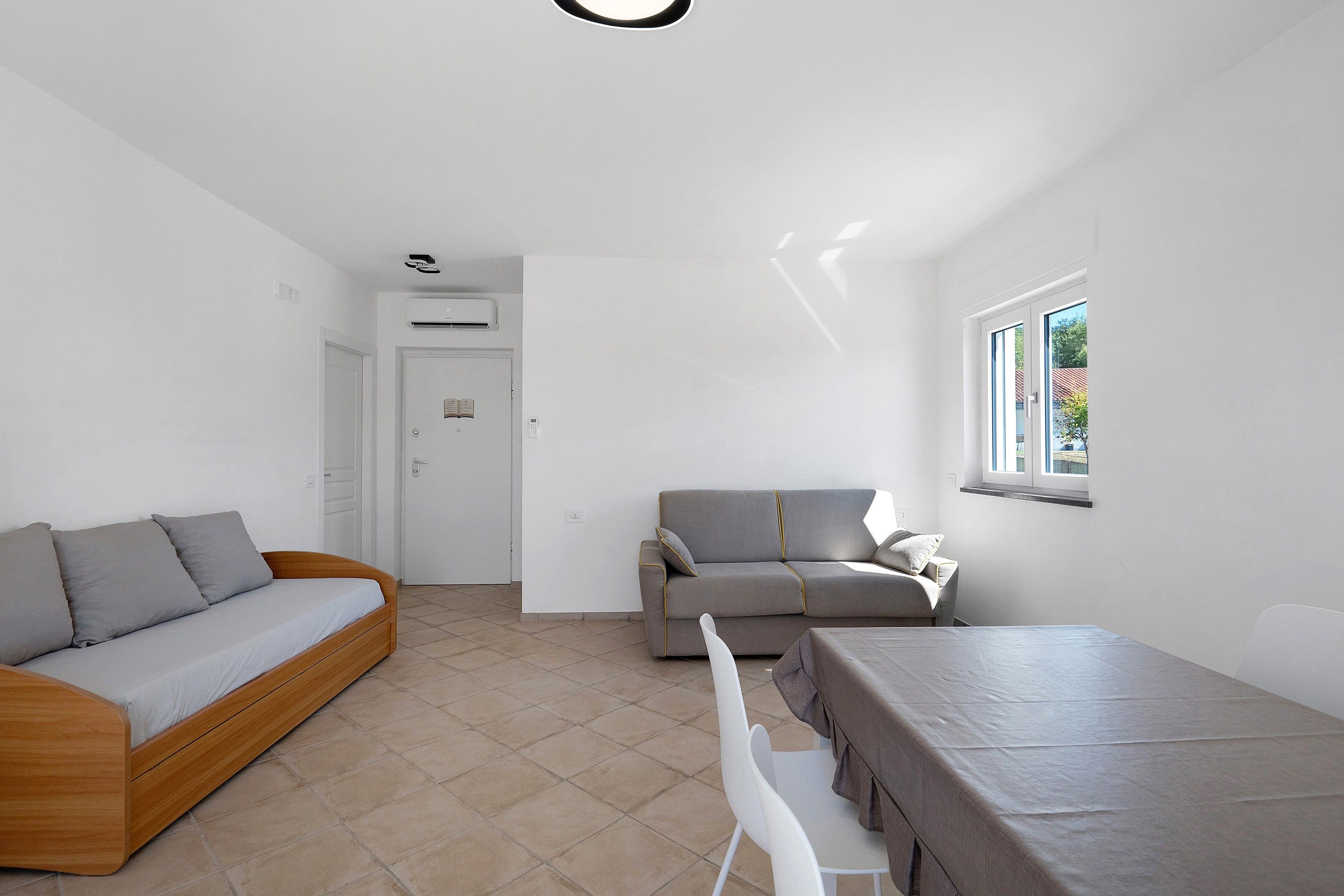 Un espace de vie moderne et minimaliste comprenant un canapé, un divan, une table à manger et une fenêtre.