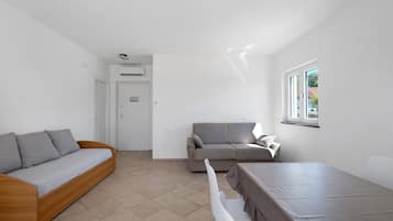 Un espace de vie moderne et minimaliste comprenant un canapé, un divan, une table à manger et une fenêtre.
