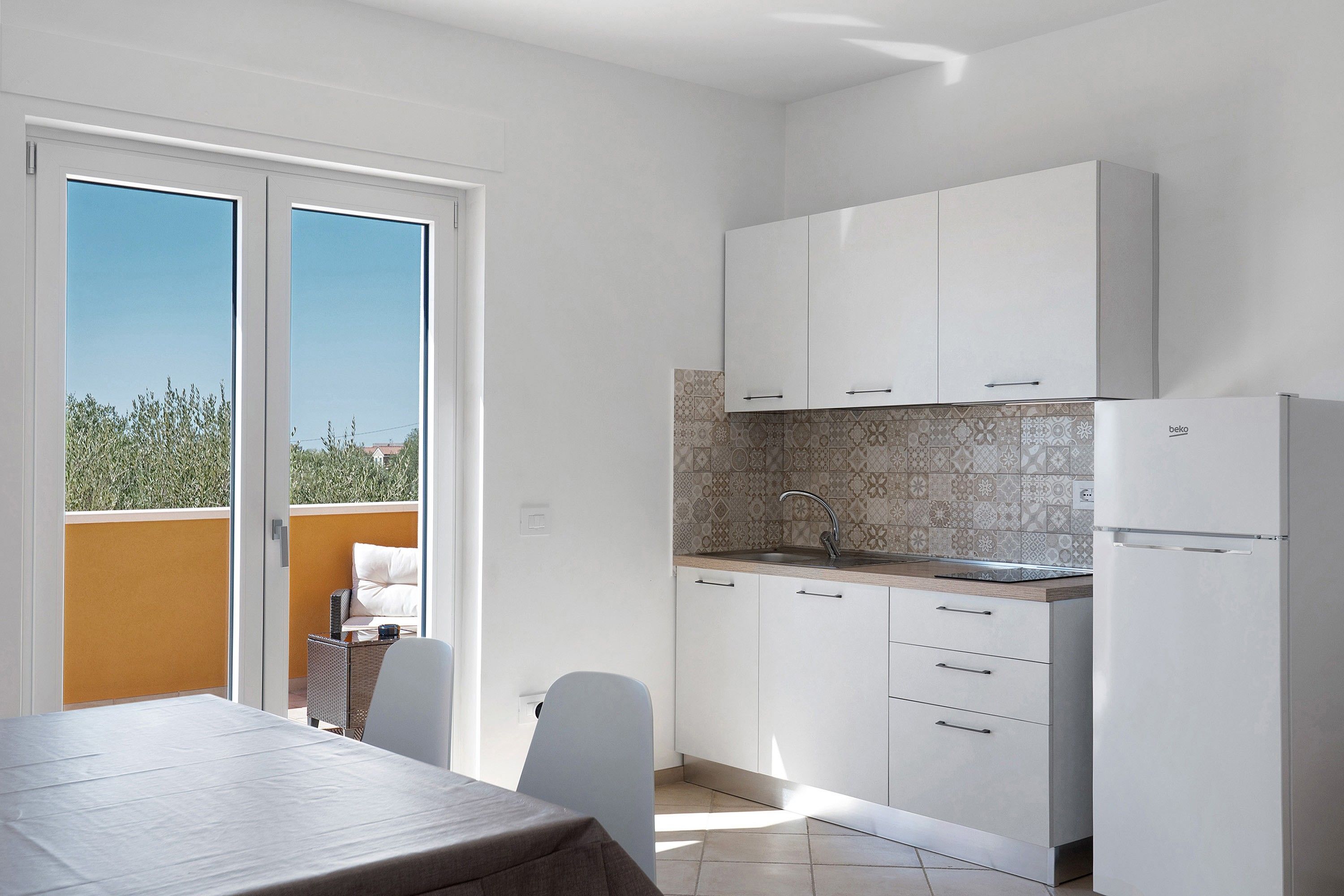 A modern kitchen with white cabinets, a built-in oven, and a sink.