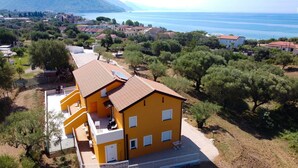 A yellow building with a red roof, a balcony, and a view of the sea.