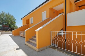 Un edifici de dues plantes amb escala i tanca de metall blanca.
